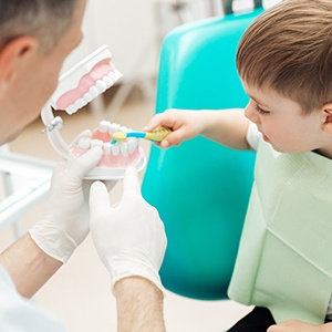 Boy learning how to brush teeth properly at dentist’s office